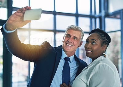 Buy stock photo Shot of two happy businesspeople posing for a selfie together in the office