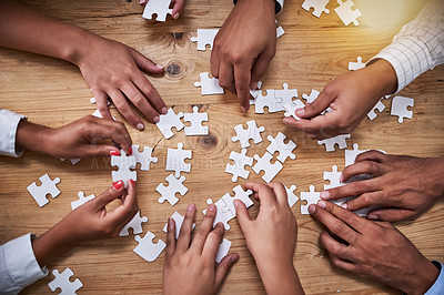 Buy stock photo High angle shot of a group of unidentifiable businesspeople building a puzzle together in the office