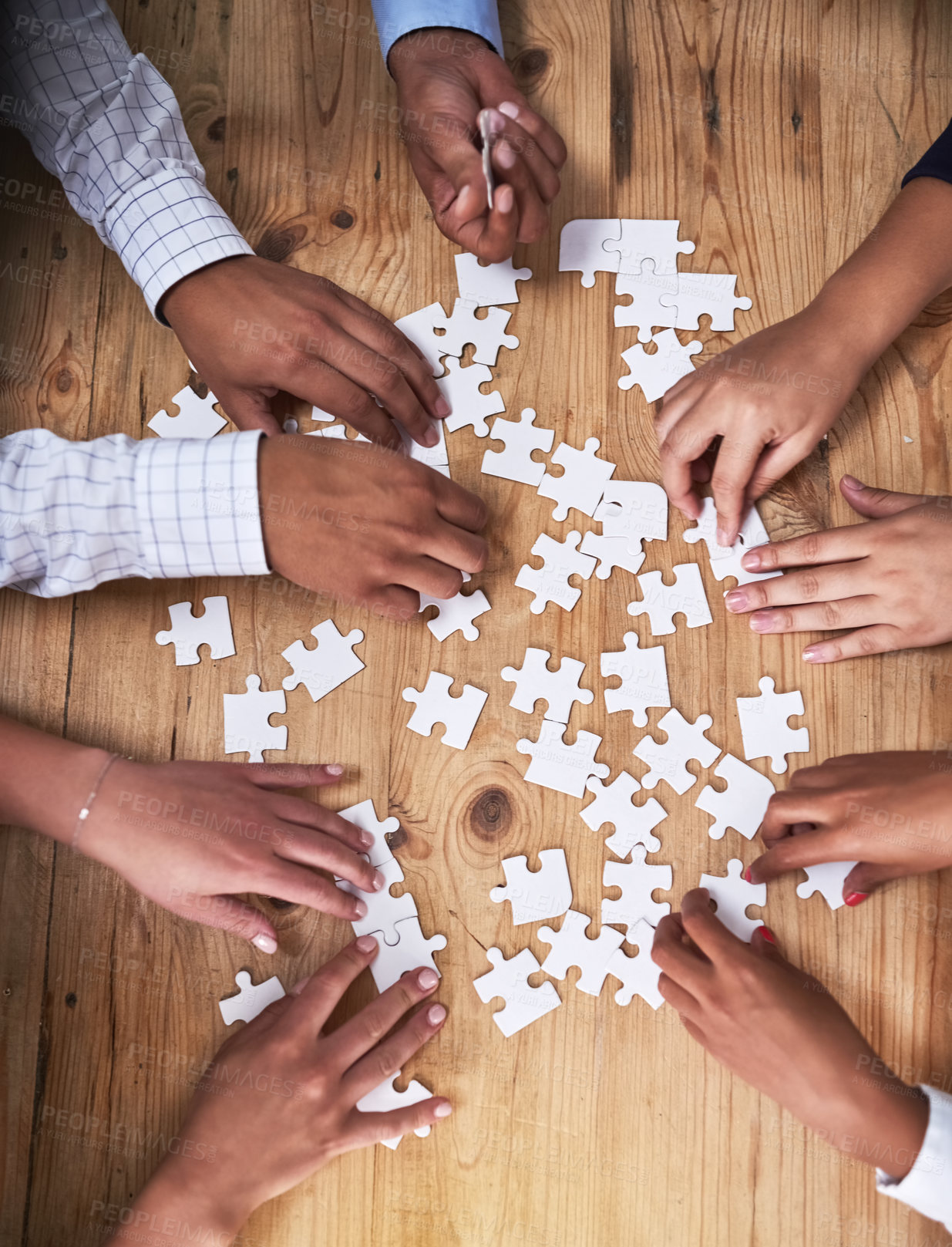 Buy stock photo High angle shot of a group of unidentifiable businesspeople building a puzzle together in the office