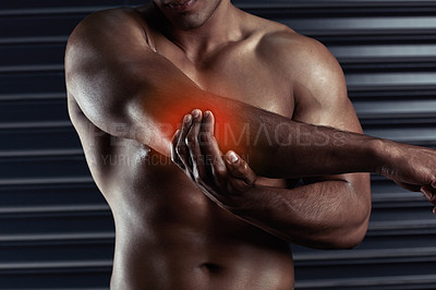 Buy stock photo Shot of an unrecognizable young man holding his elbow in pain during a workout