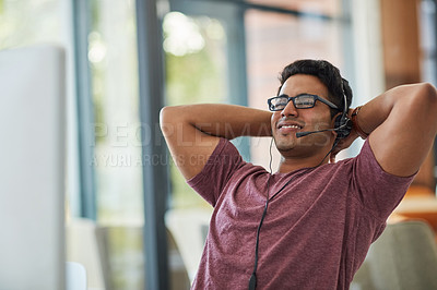 Buy stock photo Shot of a call centre agent looking relaxed at his desk