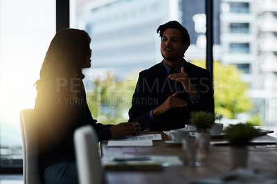 Buy stock photo Shot of two silhouetted businesspeople having a meeting in the boardroom