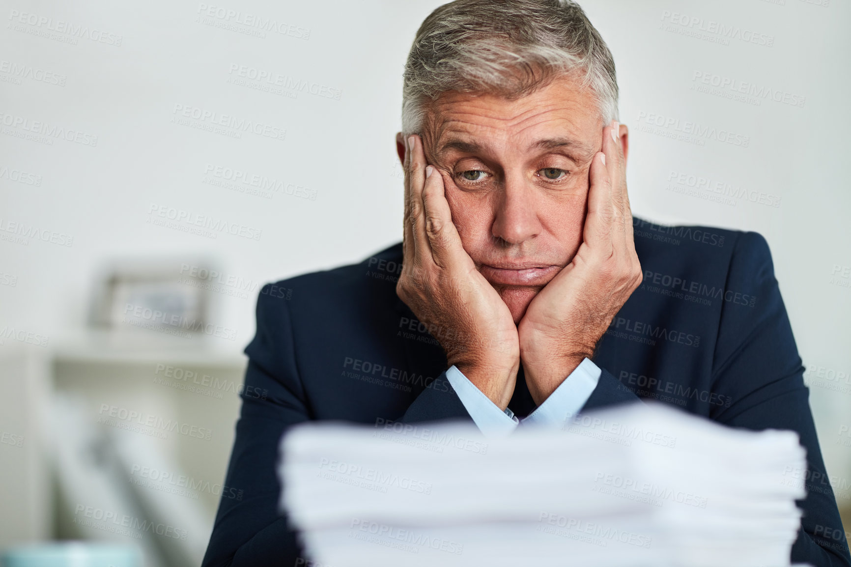 Buy stock photo Shot of a mature businessman looking at paperwork and feeling overwhelmed
