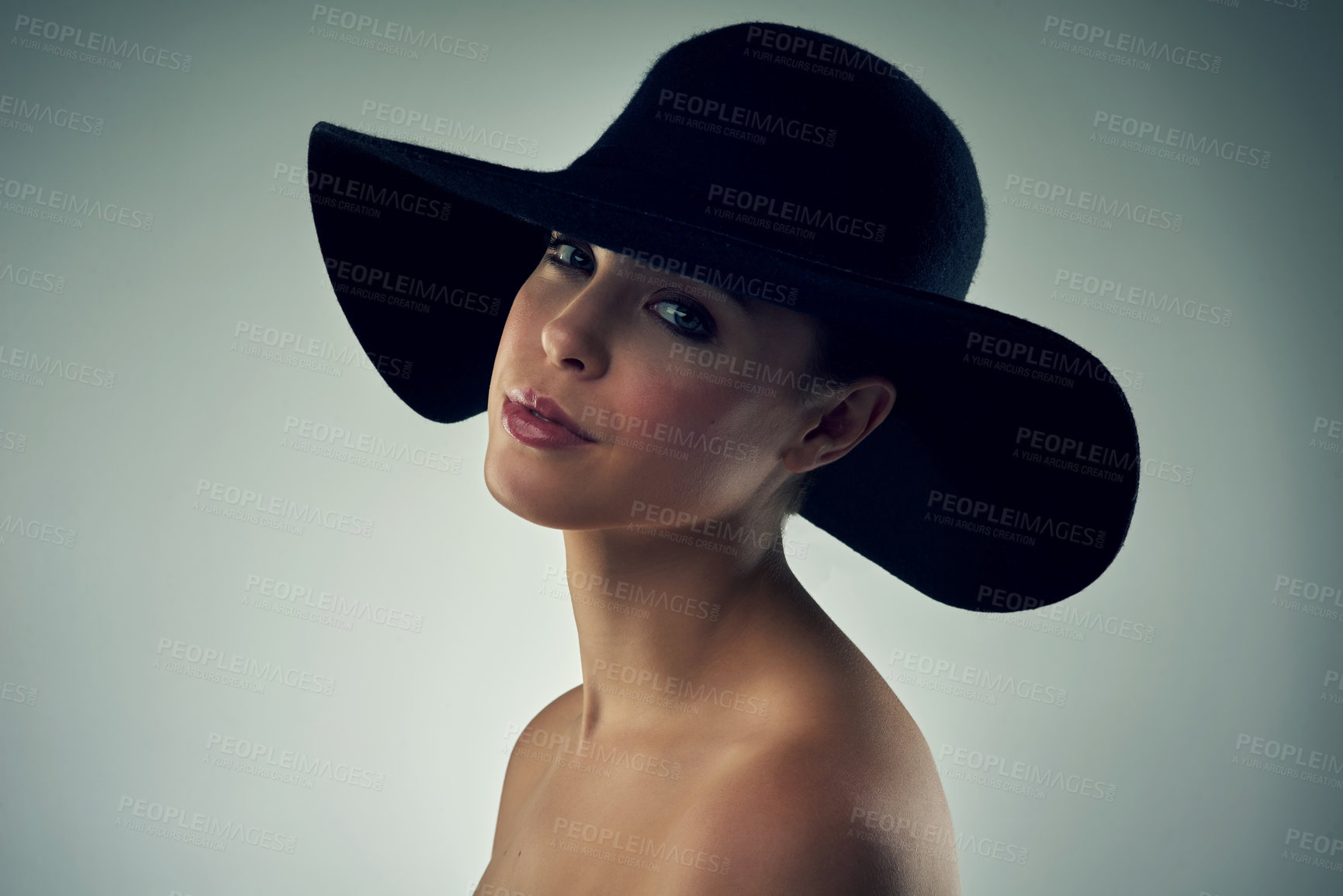 Buy stock photo Studio portrait of a beautiful young woman wearing a hat against a grey background