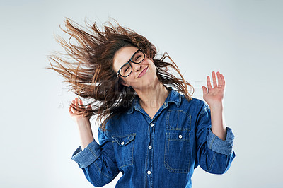 Buy stock photo Studio shot of a young woman flipping her hair against a grey background