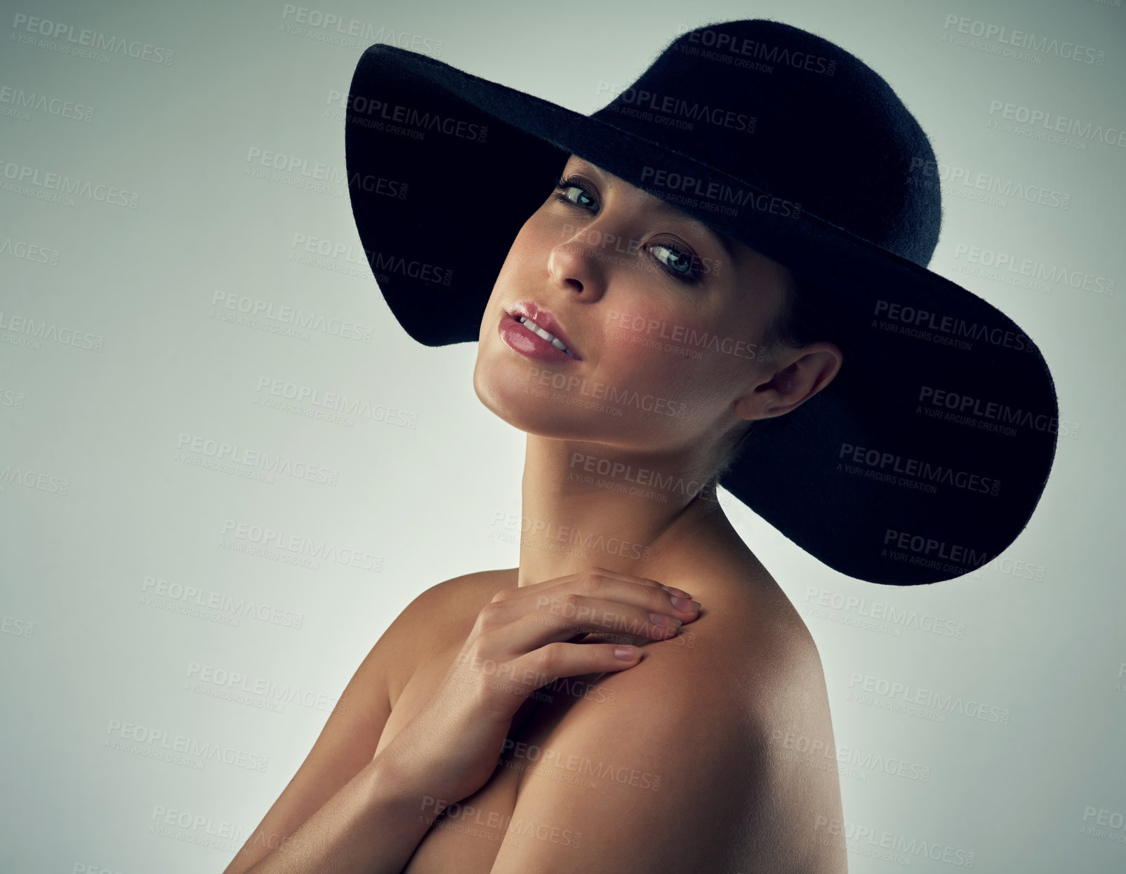 Buy stock photo Studio portrait of a beautiful young woman wearing a hat against a grey background
