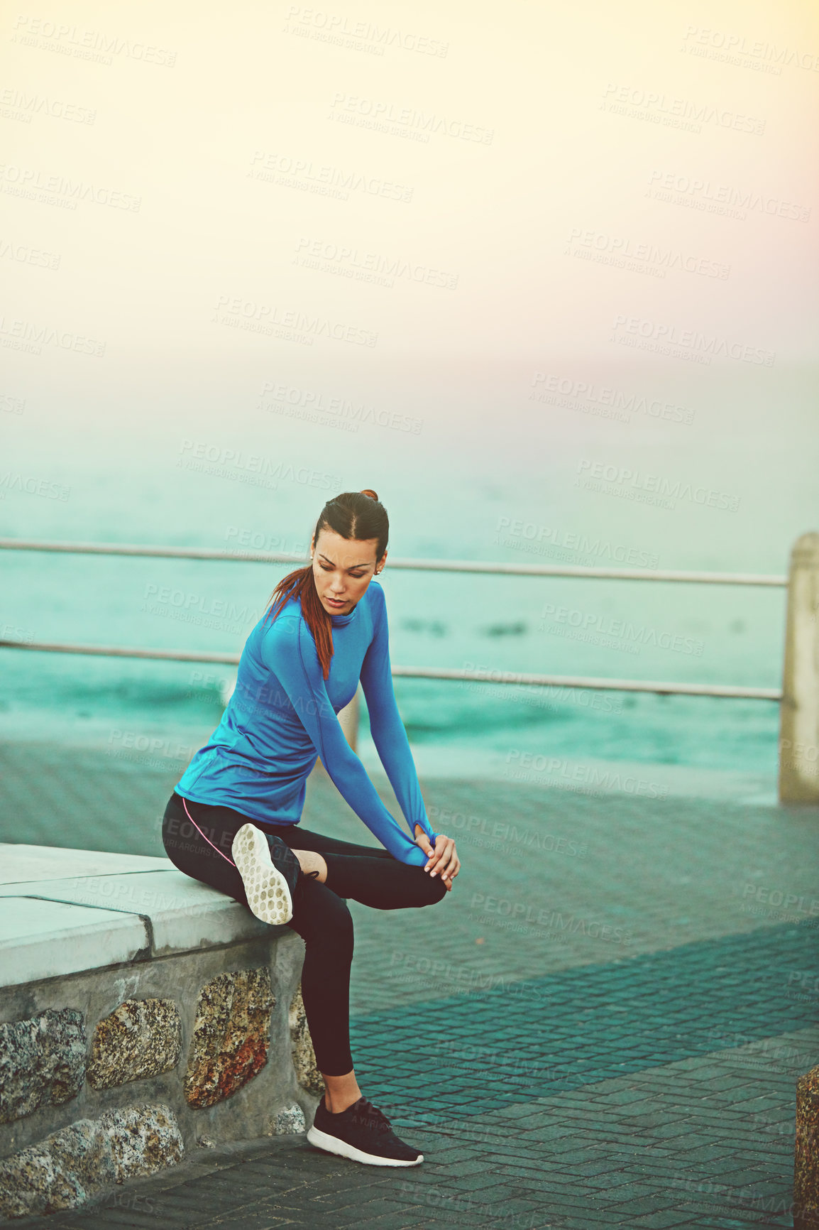 Buy stock photo Shot of a sporty young woman stretching before her run