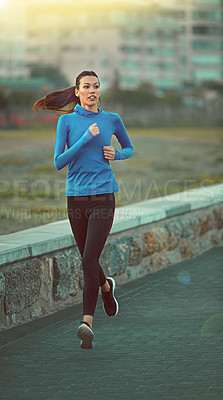 Buy stock photo Shot of a sporty young woman out running on the promenade