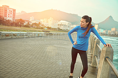 Buy stock photo Shot of a sporty young woman taking a break after her run