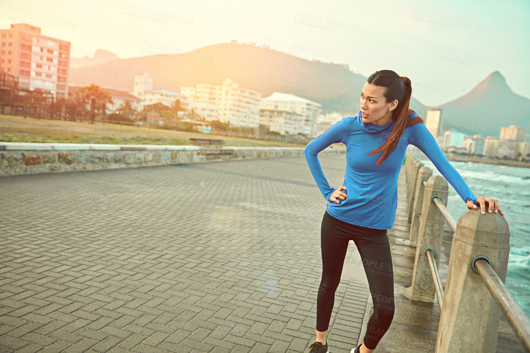 Buy stock photo Shot of a sporty young woman taking a break after her run