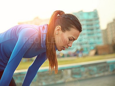 Buy stock photo Shot of a sporty young woman taking a break after her run