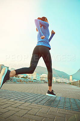 Buy stock photo Shot of a sporty young woman out running on the promenade