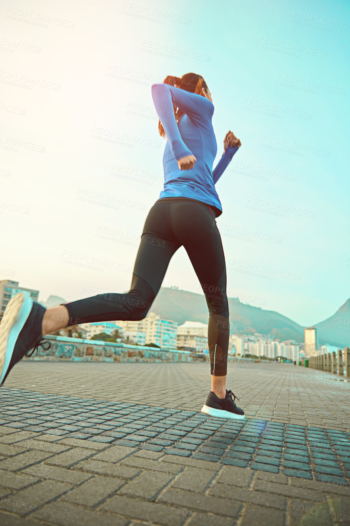 Buy stock photo Shot of a sporty young woman out running on the promenade