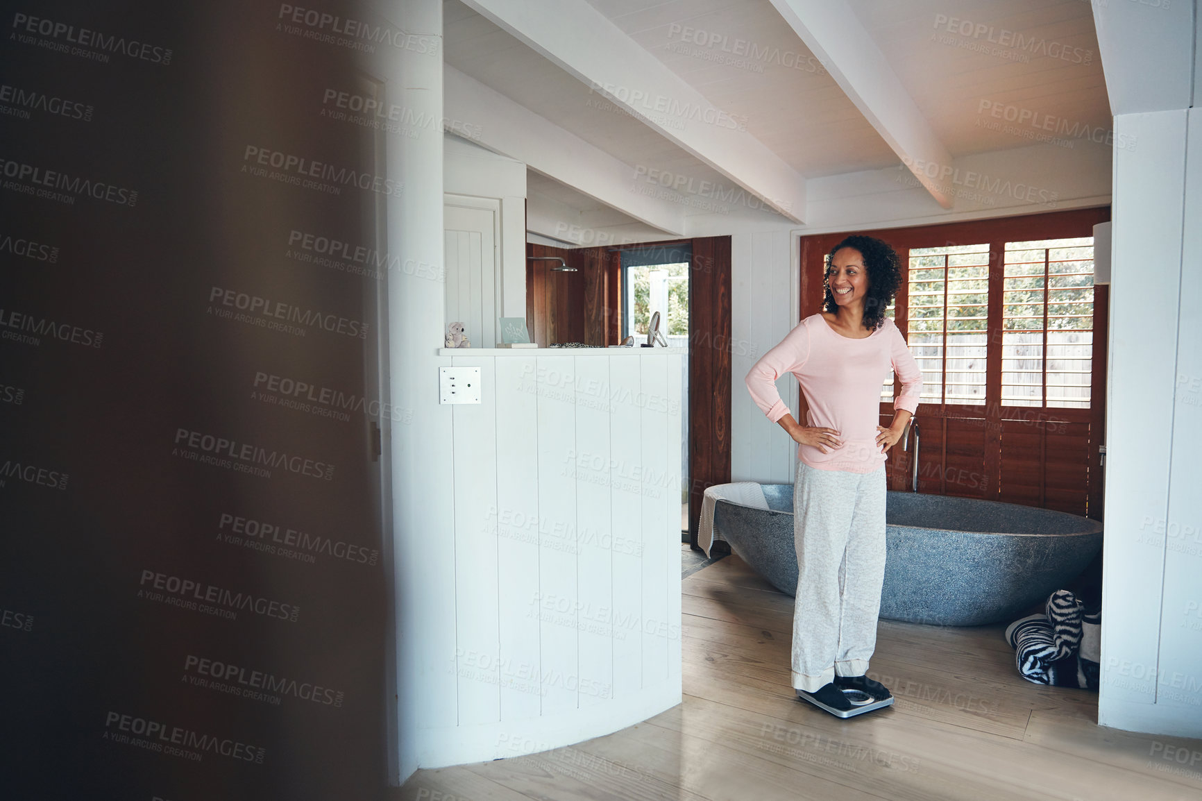 Buy stock photo Shot of a happy mature woman wishing herself on a scale in the bathroom