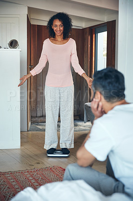 Buy stock photo Shot of a mature woman weighing herself on a scale while her husband watches
