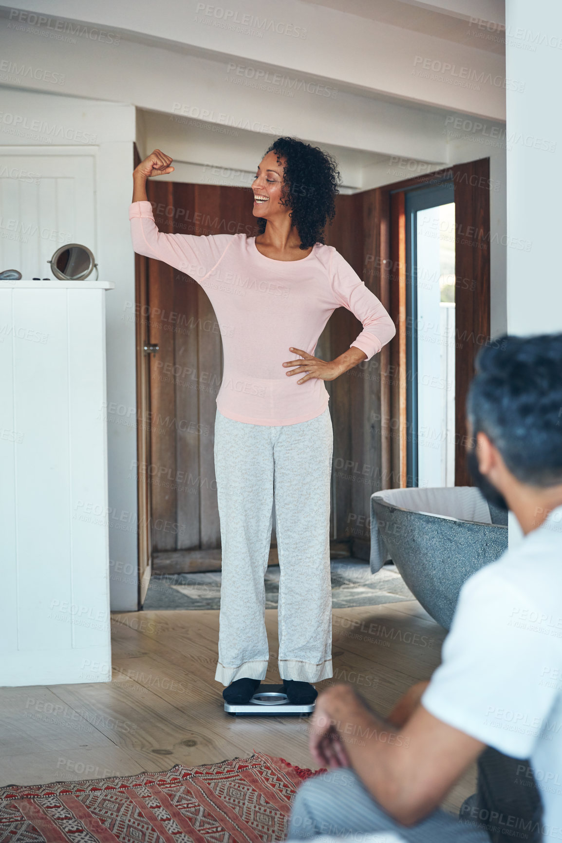 Buy stock photo Shot of a mature woman weighing herself on a scale while her husband watches