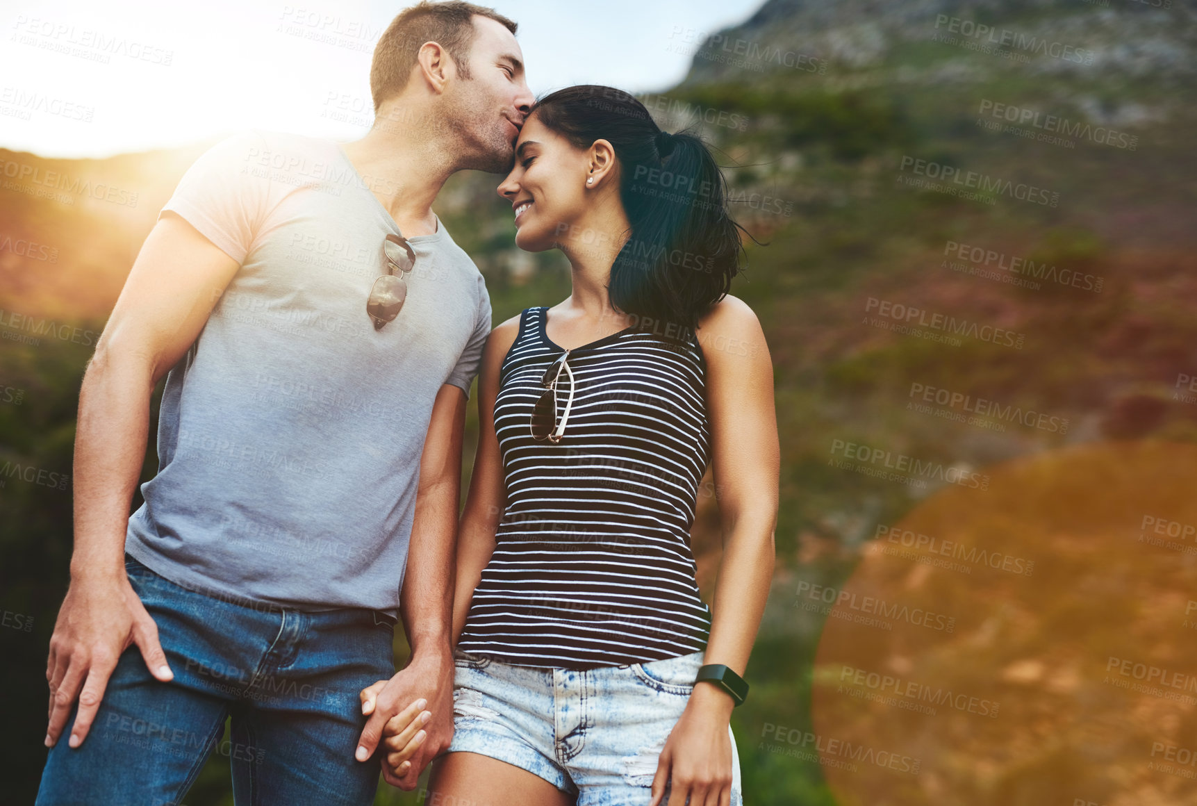 Buy stock photo Mountain, kiss or happy couple holding hands on date with wellness or care for romance or adventure. Bokeh, smile or man with woman on holiday vacation together for bond or support in nature or park