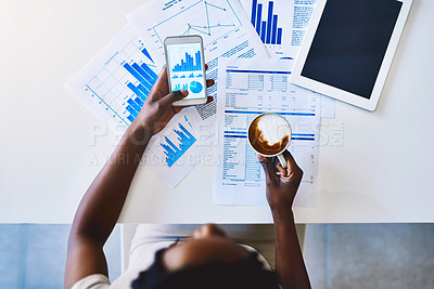 Buy stock photo High angle shot of an unidentifiable businesswoman drinking coffee while analyzing graphs on her smartphone