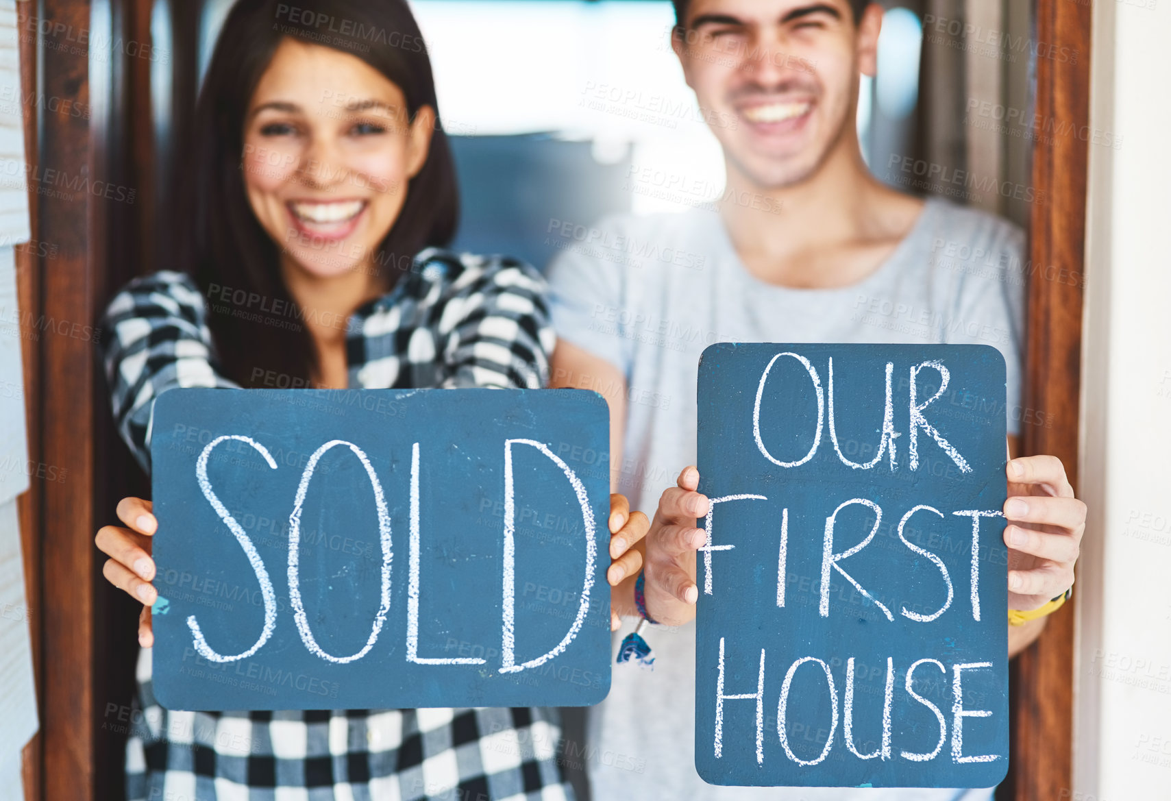 Buy stock photo Portrait of a happy couple holding signs as they move into their new house