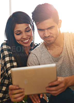 Buy stock photo Shot of a happy young couple taking a break with their tablet while moving into their new home