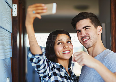 Buy stock photo Shot of a happy young couple posing for a selfie in their new home