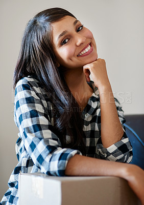 Buy stock photo Portrait of a happy young woman leaning on a cardboard box on moving day