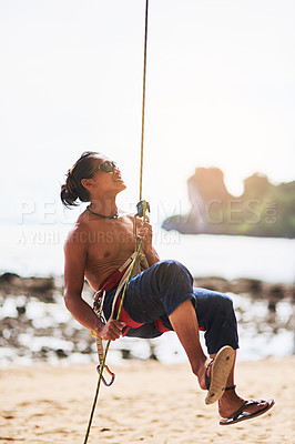 Buy stock photo Shot of a young man climbing a mountain on a sunny day