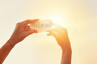 Buy stock photo Love, sunshine and hands of person with paper in outdoor for confession, announcement or valentines day gesture . Low angle, sky and romantic woman with message for support, kindness or compassion