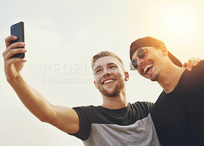 Buy stock photo Shot of two happy friends posing for a selfie together outside