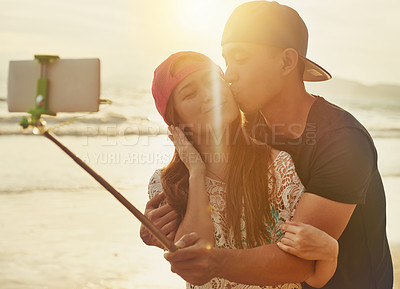 Buy stock photo Shot of an affectionate couple taking a selfie on the beach