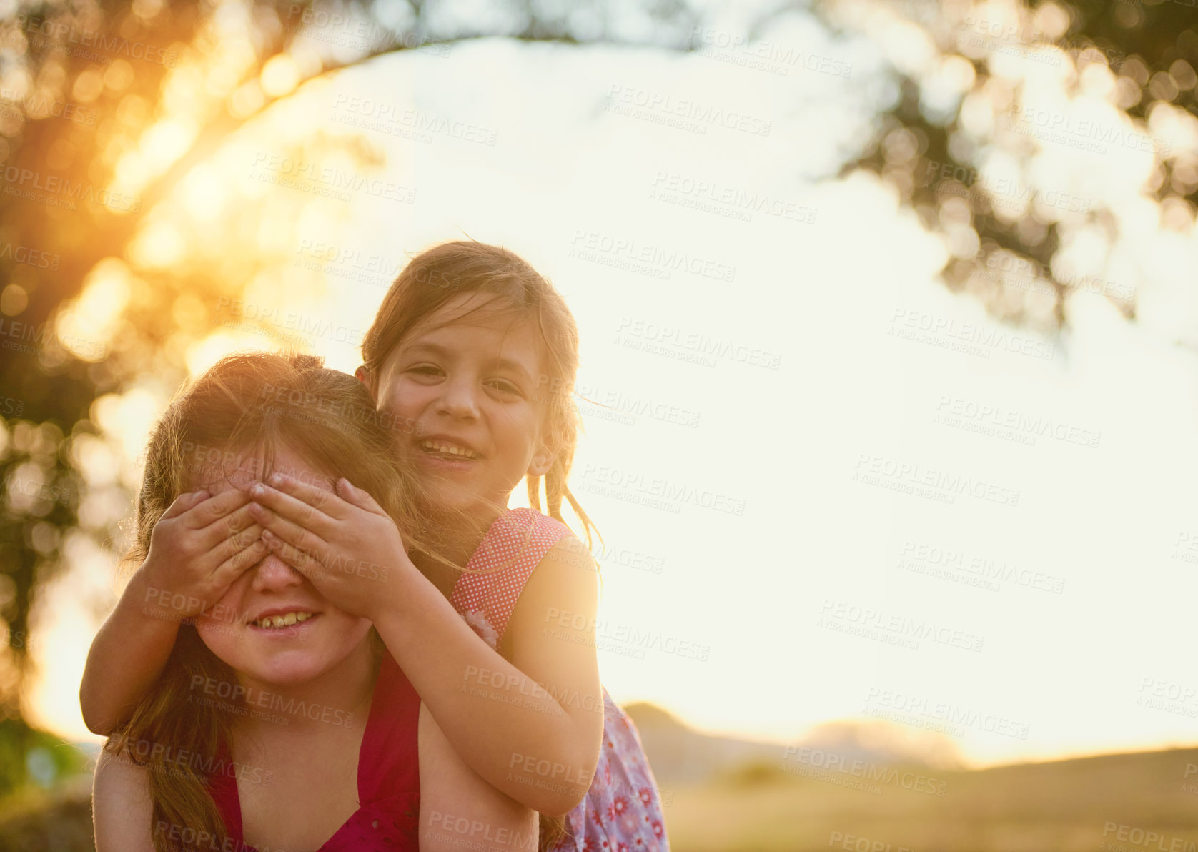 Buy stock photo Children, happy and piggyback with cover eyes or sunshine in backyard playing, games and outdoor. Kids, siblings and together in nature for summer bonding activity for happiness, youth and friends