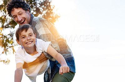 Buy stock photo Portrait of a happy father playfully carrying his son during a fun day outdoors