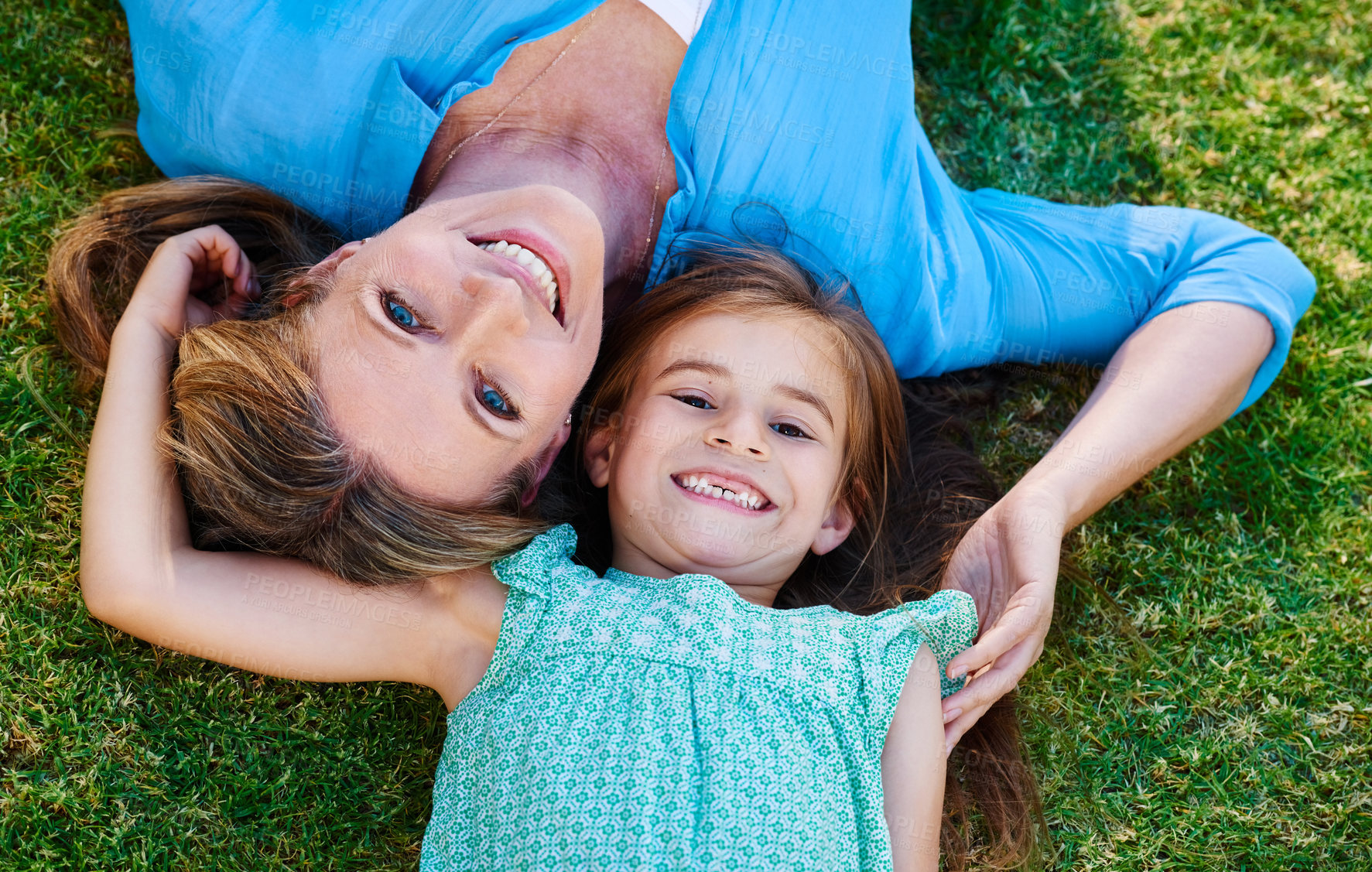 Buy stock photo High angle shot of a happy mother and daughter relaxing on the grass together outside
