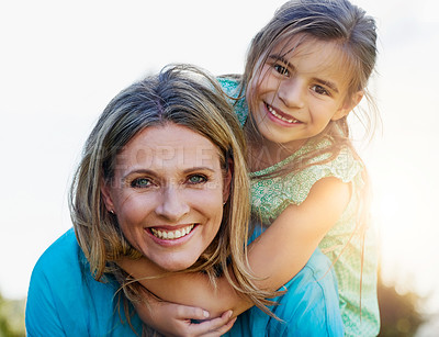 Buy stock photo Portrait of a happy mother and daughter enjoying a piggyback ride outdoors