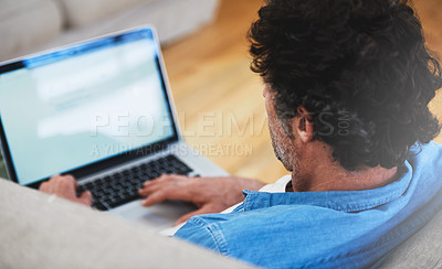 Buy stock photo Rearview shot of a bachelor relaxing on the sofa with his laptop