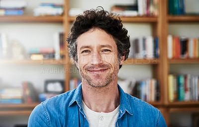 Buy stock photo Shot of a happy bachelor posing in front of a bookshelf at home
