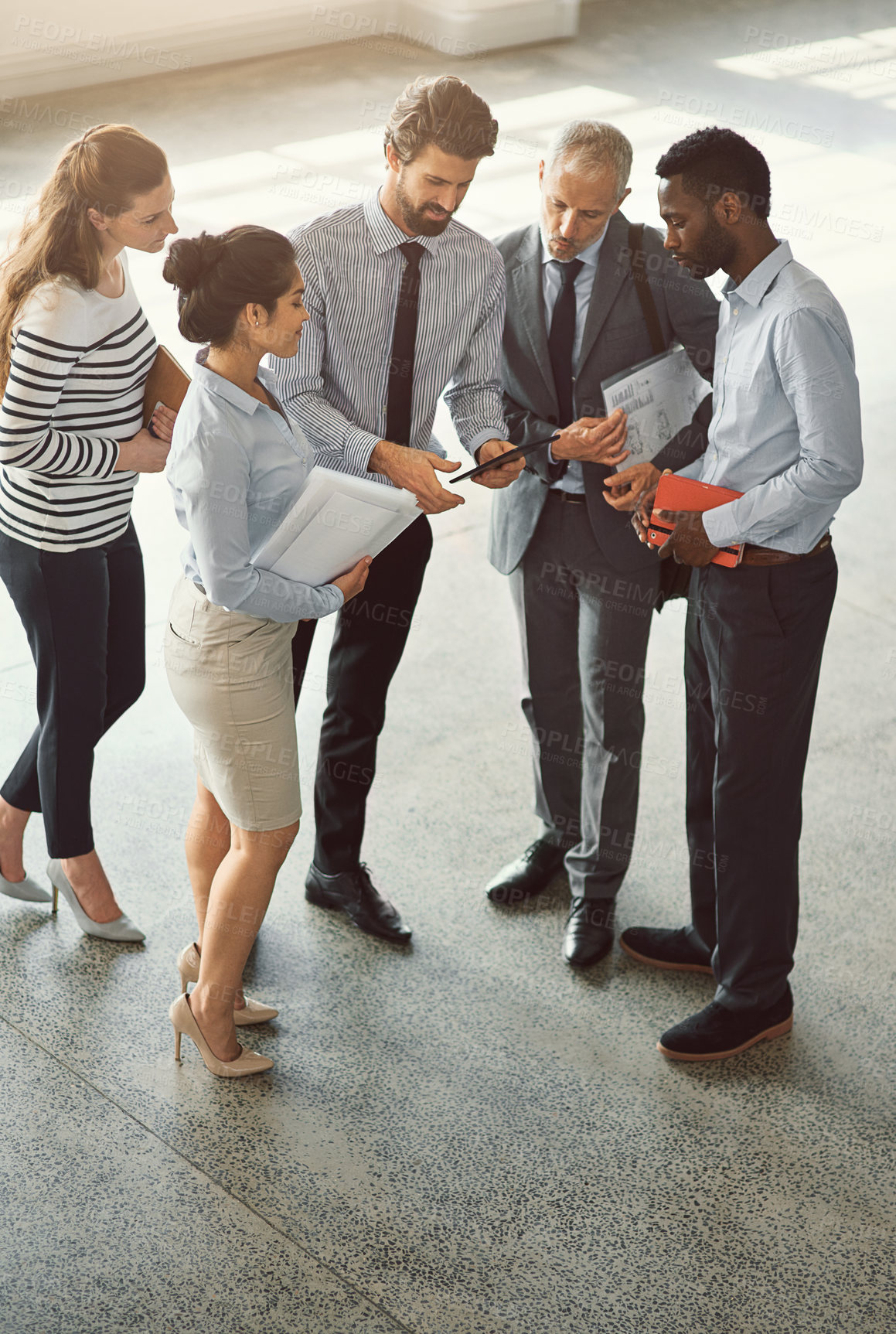 Buy stock photo High angle shot of a group of businesspeople talking together while standing in an office lobby