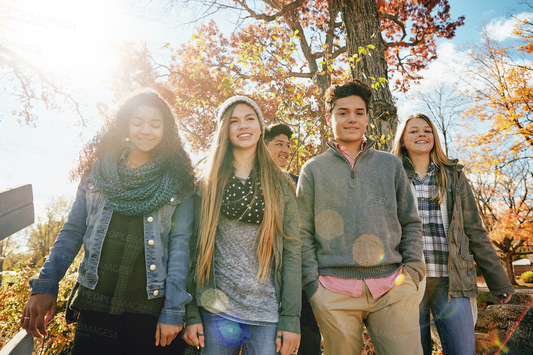 Buy stock photo Smile, portrait and teenage friends with bridge, walking and bonding together with nature. Conversation, boys and girls with happiness, lens flare and travel with journey, weekend break and explore