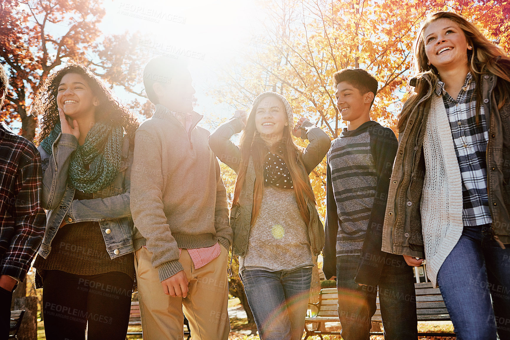 Buy stock photo Teen, best friends and laugh in park with autumn weather, funny conversation and bonding together. Low angle, flare and happy kids outdoor with fall season, weekend hangout and humor for discussion.