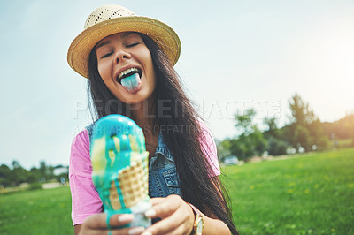 Buy stock photo Shot of an attractive young woman enjoying an ice cream in the park