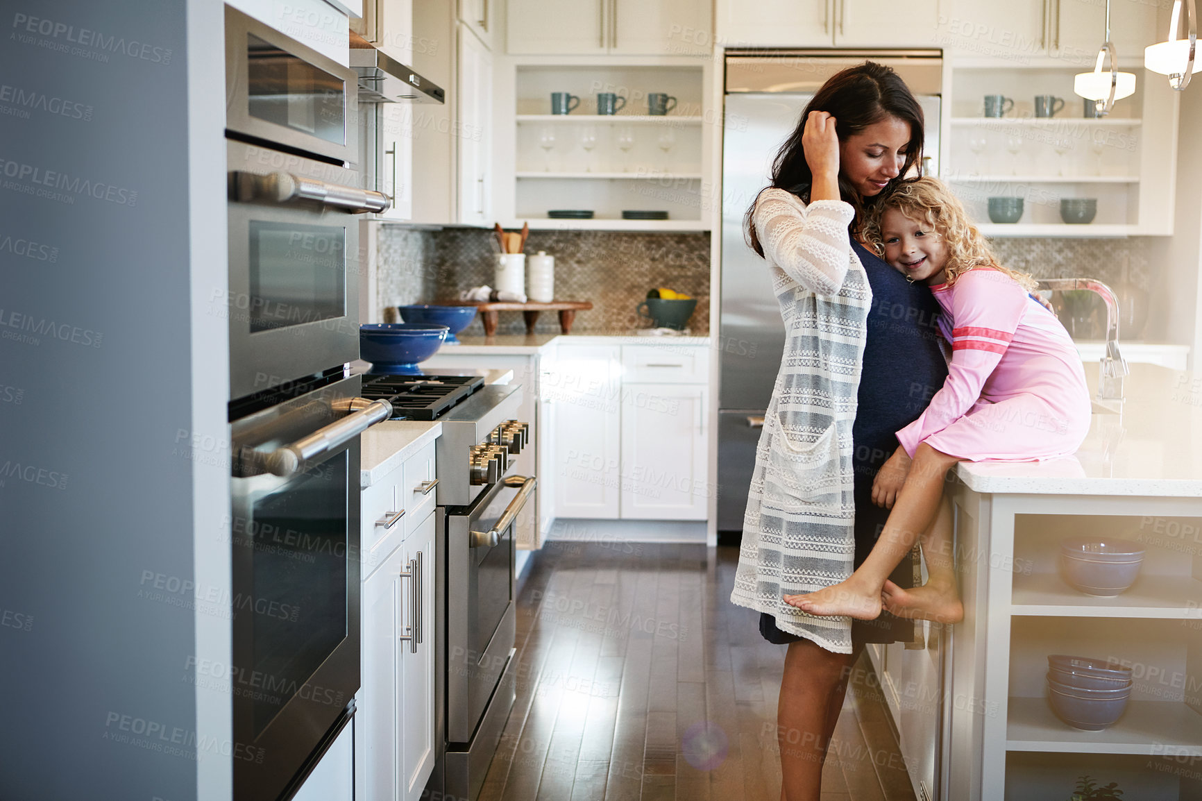 Buy stock photo Cropped shot of a pregnant woman bonding with her little daughter at home