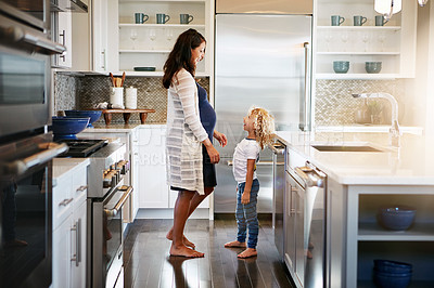 Buy stock photo Shot of a pregnant woman bonding with her little son at home