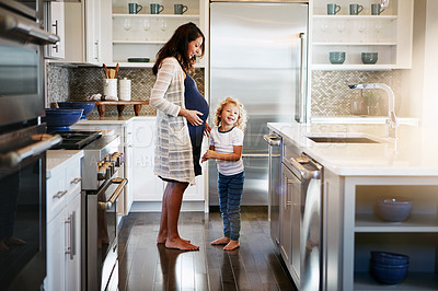 Buy stock photo Shot of a pregnant woman bonding with her little son at home