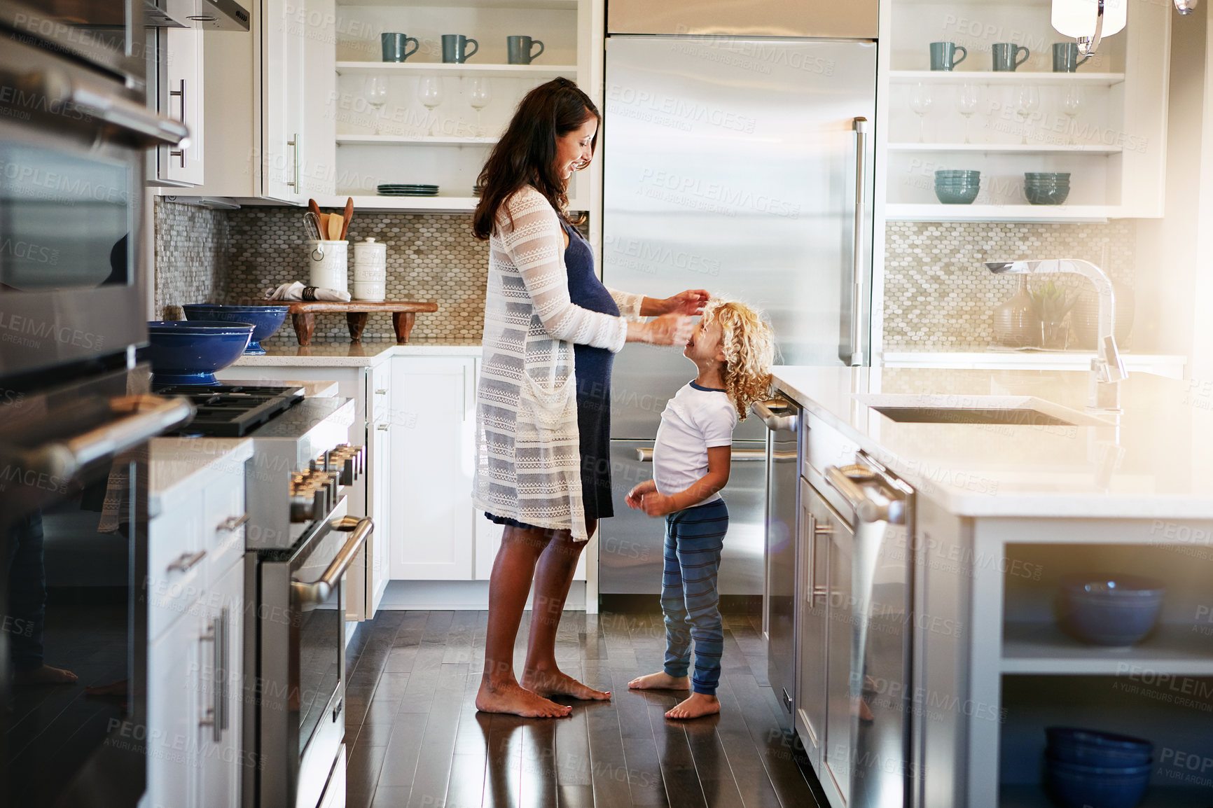 Buy stock photo Shot of a pregnant woman bonding with her little son at home