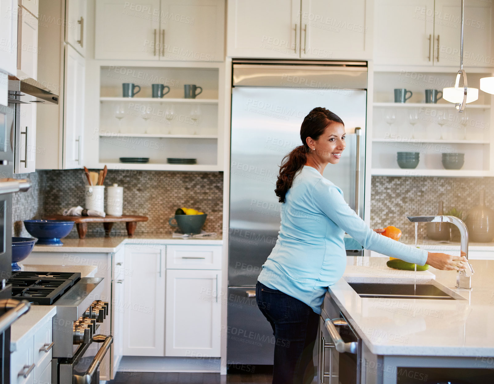 Buy stock photo Cropped shot of a pregnant woman washing vegetables in the kitchen sink