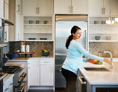 Buy stock photo Cropped shot of a pregnant woman washing vegetables in the kitchen sink