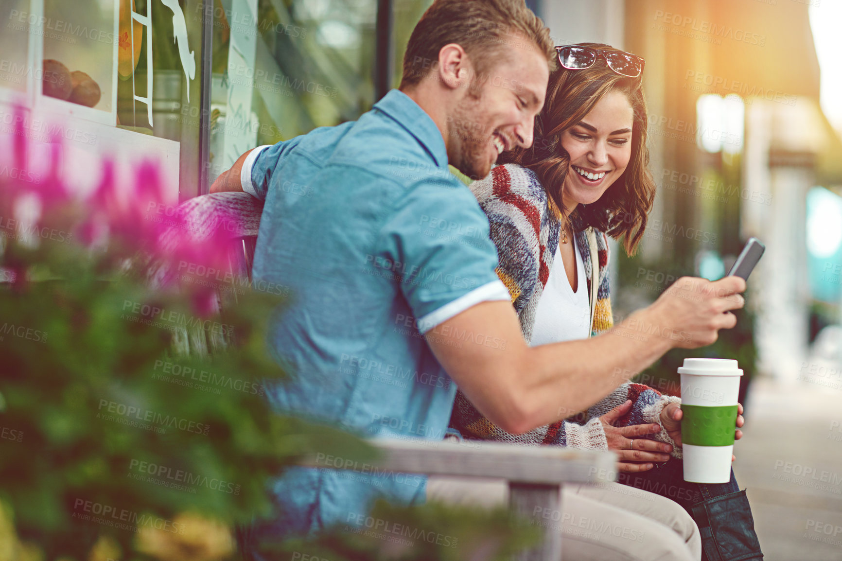 Buy stock photo Shot of a happy young couple using a smartphone together while spending the day downtown