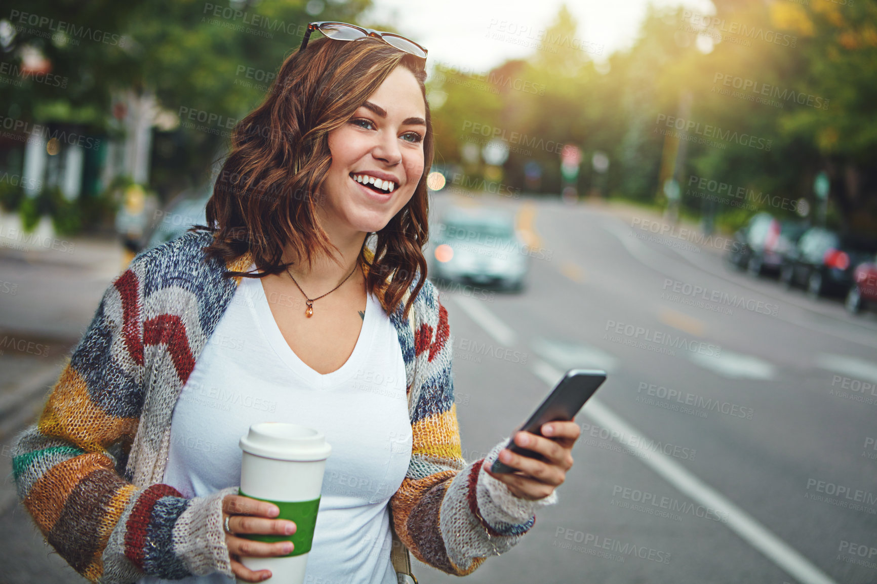 Buy stock photo Shot of a happy young woman using her cellphone while taking a walk downtown