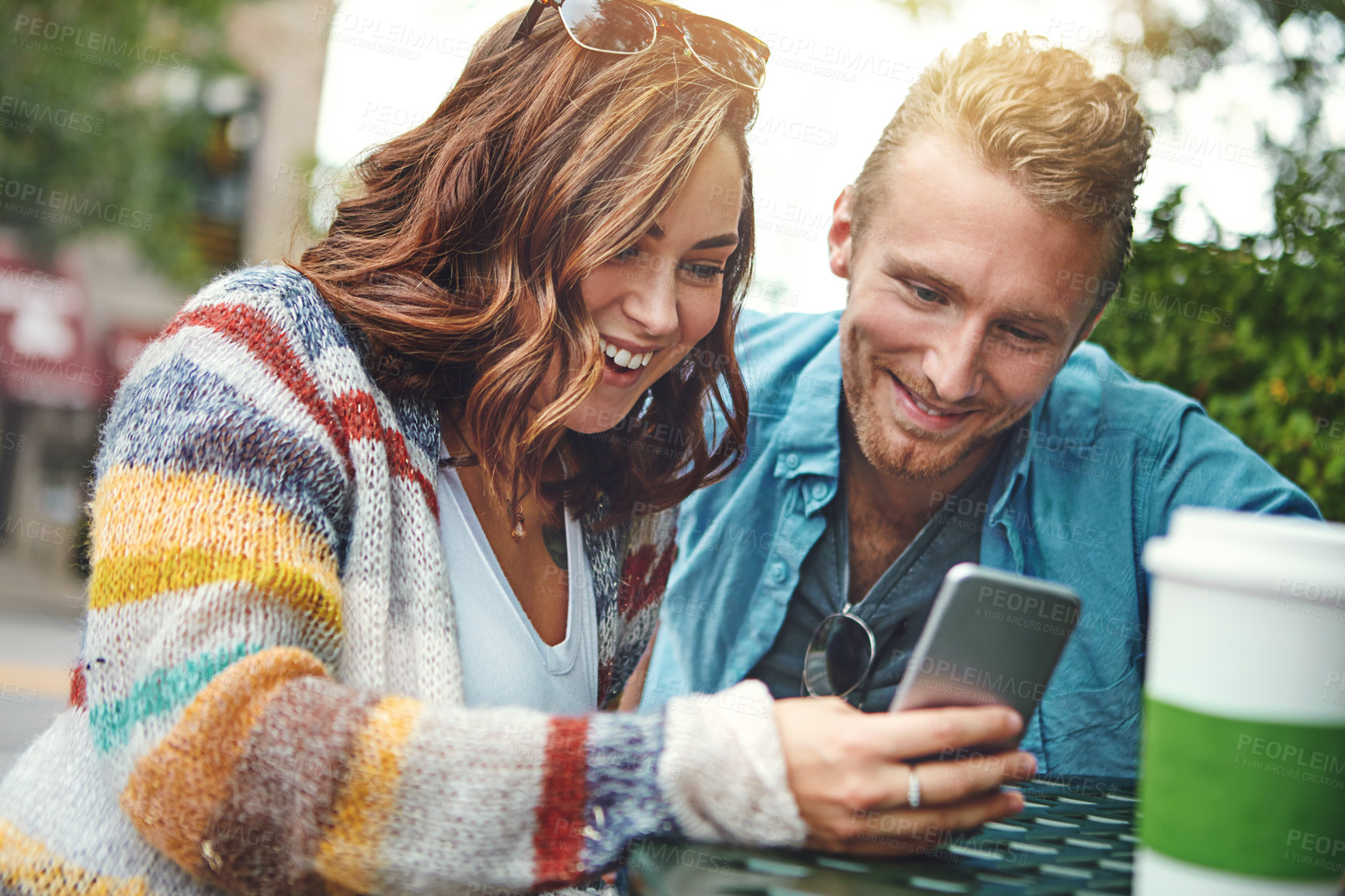 Buy stock photo Shot of a happy young couple using a smartphone together while spending the day downtown