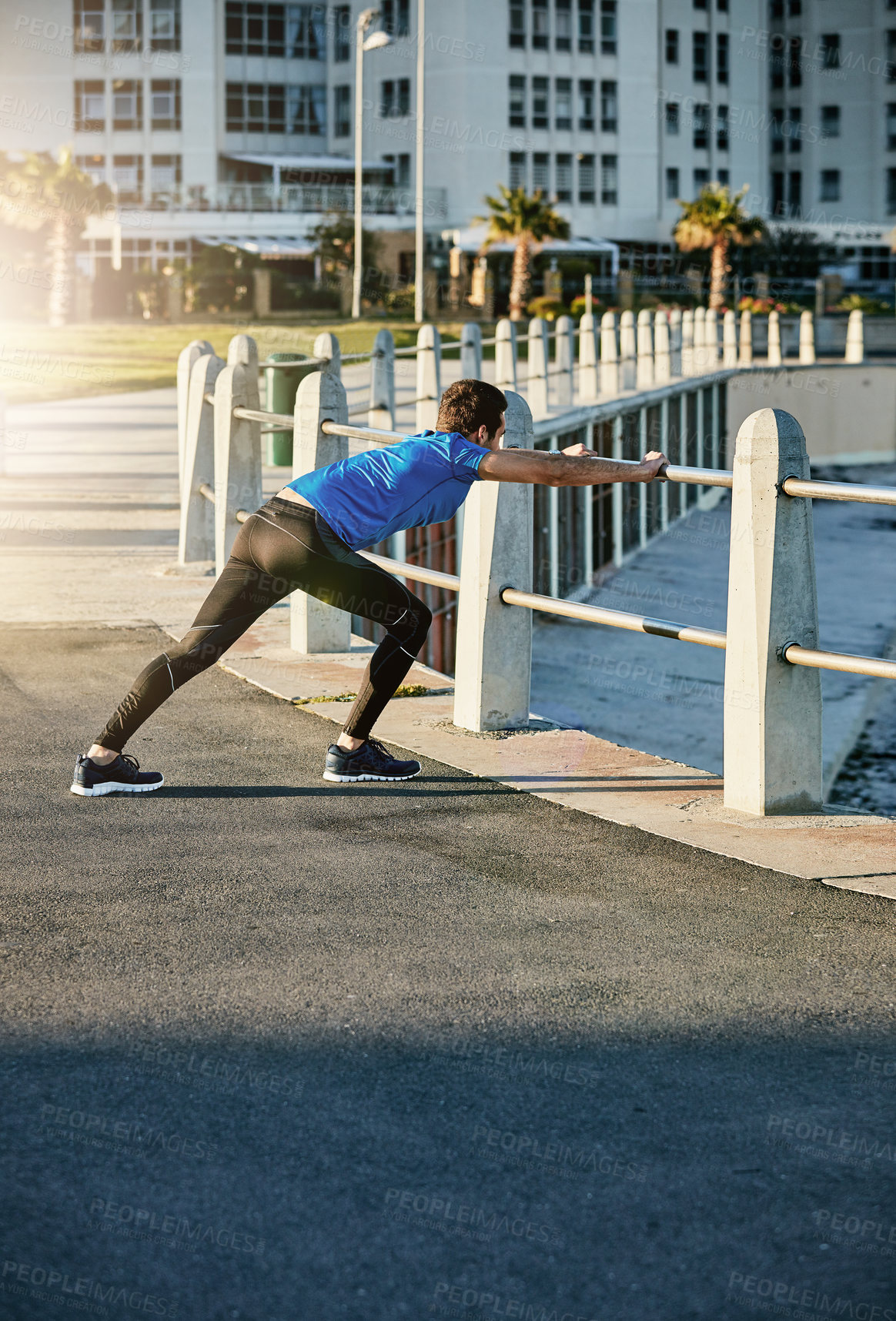 Buy stock photo Shot of a young man stretching outside before his run